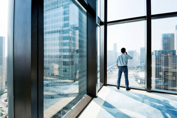 istock Businessman standing by the window and using phone 948603024