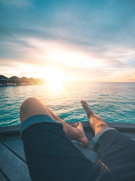Point of view shot of a young man watching the sunset on an island in the Maldives. Shot from a personal perspective.