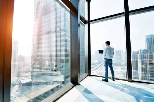 istock Businessman standing by the window and using laptop 948603174