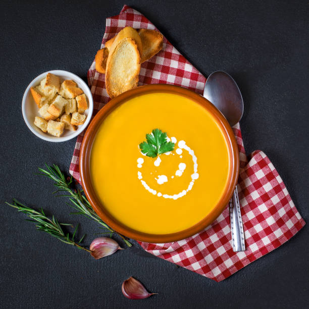 istock Pumpkin and carrot soup with cream and herbs on black concrete background with copy space.  Top view 948603268