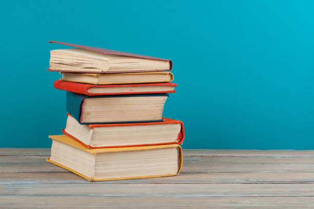 istock Book stacking. Open hardback books on wooden table and blue background. Back to school. Copy space for ad text 948609648
