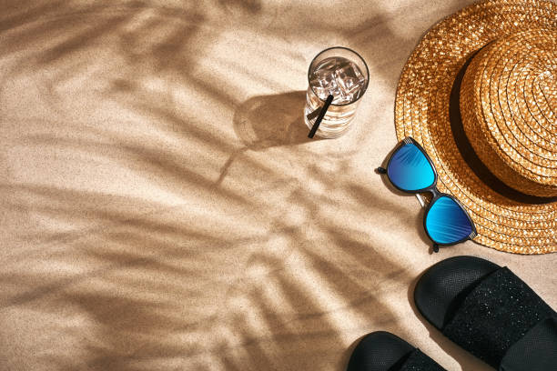 istock Sandal, straw hat and sunglasses on a sandy background, top view 948611494