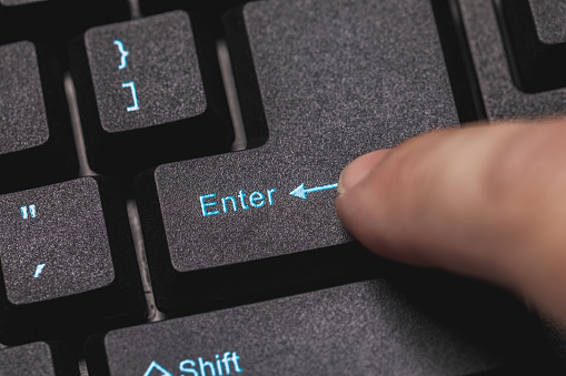 Close up of a finger hitting the Enter key on a new computer keyboard