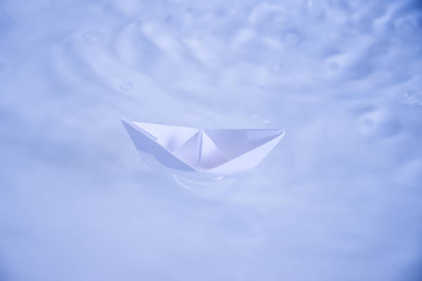 istock small folded paper ship on clear blue and turquoise water 948625122