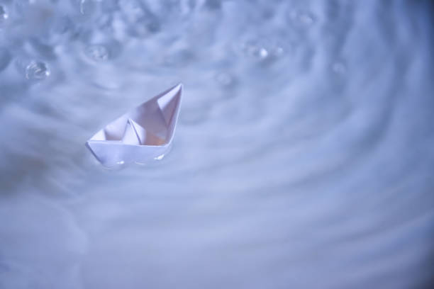 istock small folded paper ship on clear blue and turquoise water 948625256