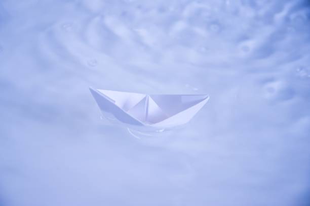 istock small folded paper ship on clear blue and turquoise water 948625338