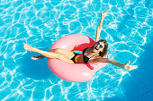 Beautiful crazy woman relaxing on inflatable ring in blue swimming pool