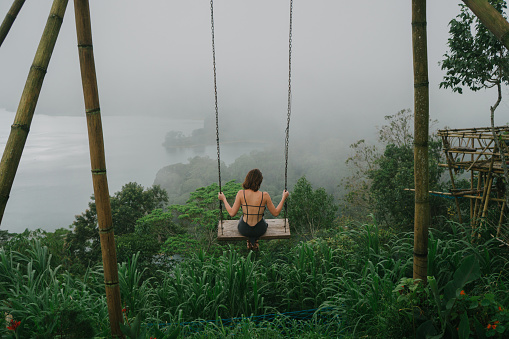Young Caucasian woman  on the swing with view of lake in Bali