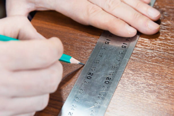 istock Close-up Men's hands draw a pencil on the ruler with a sub-standard template for cutting out furniture details next to the jigsaw and furniture clips 948648230