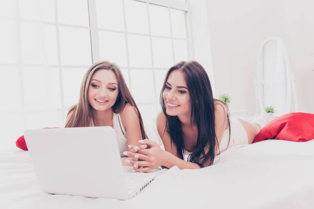 istock Cheerful happy girls lying on  bed and using modern laptop 948651970