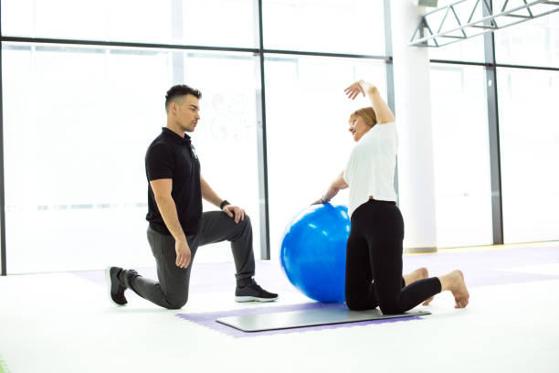 istock Mature woman doing exercise with personal trainer 948654058
