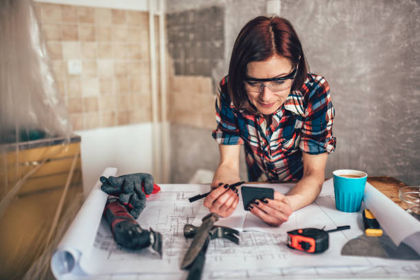 woman using smart phone while renovating kitchen - female construction telephone building contractor imagens e fotografias de stock