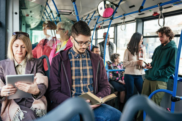 Businesswoman using tablet and student reading book in the bus