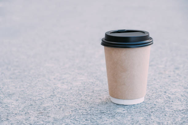 istock coffee in brown cardboard cup with black cap on asphalt as background 948675200