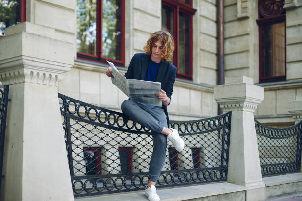 istock Man reading newspaper near old style building 948675426