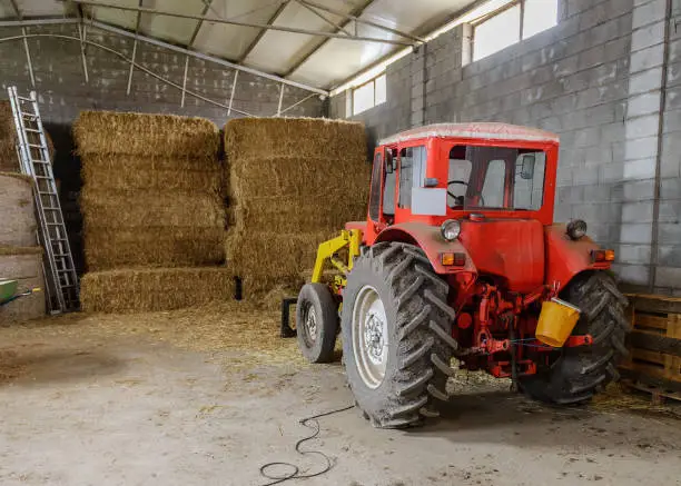 image of tractor in a shed with haystacks