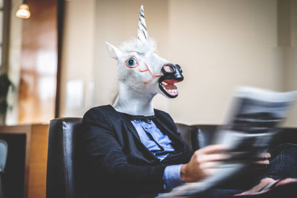 istock Business man with Unicorn Mask Reading Newspaper at Office 948682542