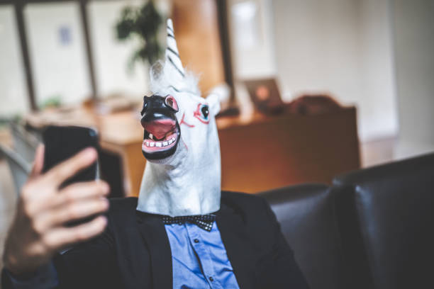 istock Business man with Unicorn Mask Taking a Selfie at Office 948683060