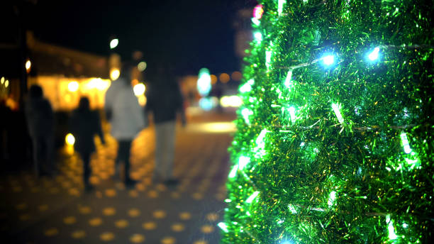 istock Sparkling lights on Christmas tree, family with children strolling on background 948704526