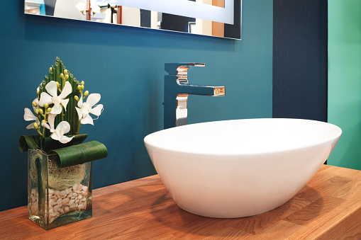 Luxury modern style faucet mixer on a white round sink in beautiful dark blue bathroom