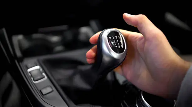 Photo of Male hand holding manual gearbox in car, test drive of new automobile, closeup