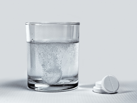 Closeup of effervescent tablets dissolving in a glass of water