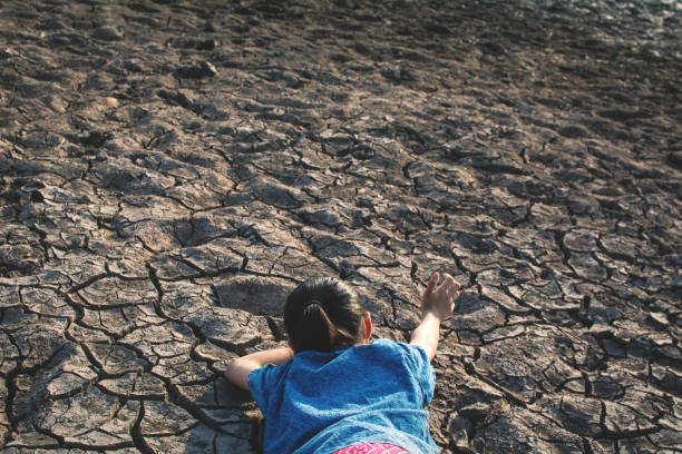 istock High Angle View Of Girl Lying On Field During Drought 948705474