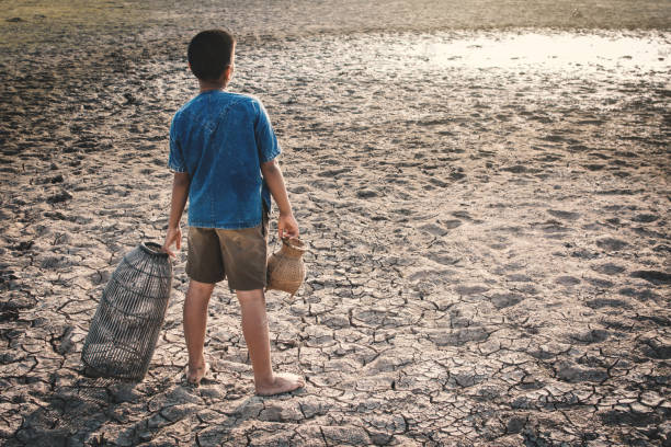 istock Rear View Of Boy Holding Pot While Standing On Field During Drought 948705510