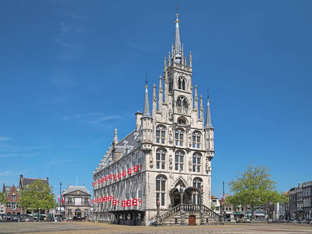 Gouda, Netherlands - May 24, 2015: Town Hall on the Markt square. This is the one of the oldest gothic town halls in the country, it was built in 1448-1459. Left of the town hall in the background is located the Waag (or Kaaswaag) - a cheese weighing house. It was built in 1668-1670 by design of the Dutch architect and painter Pieter Post. Since 1995, the Waag hosts the Gouda Cheese Museum.