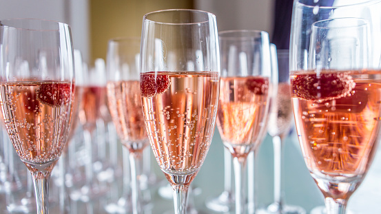 Refreshing, effervescent raspberry champagne in a multiple clear flutes