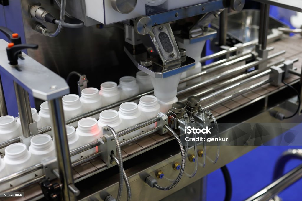 pharmaceutical packaging line Pharmaceutical packaging line. Bottle filling machine with empty plastic pill bottles. Manufacturing Stock Photo