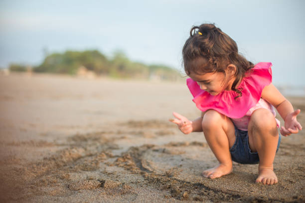 A young Japanese woman is writing on sand on the beach.