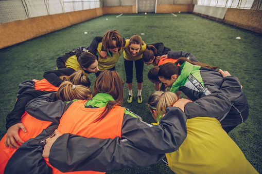 Female soccer team forming huddle on a playing field