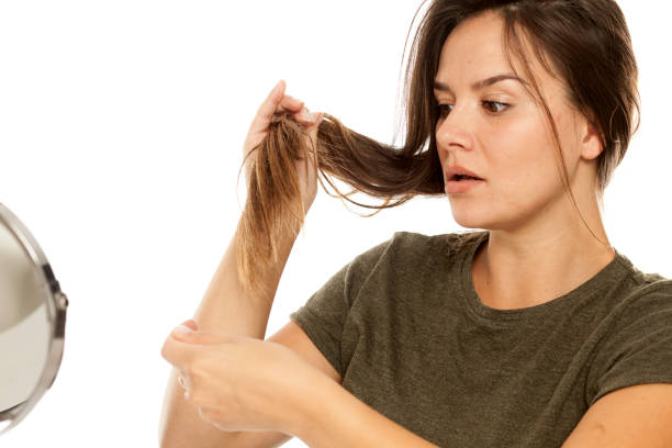 istock Nervous young woman looking at her hair on white background 948752462