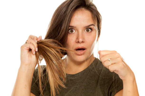giovane donna scioccata che mostra i suoi capelli smarriti su sfondo bianco - isolated on white brown white anxiety foto e immagini stock