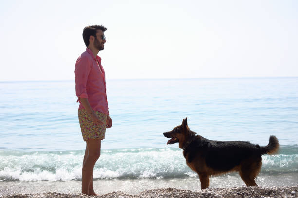 A woman and her German Shepherd dog are enjoying the view by the river during the summer vacation.