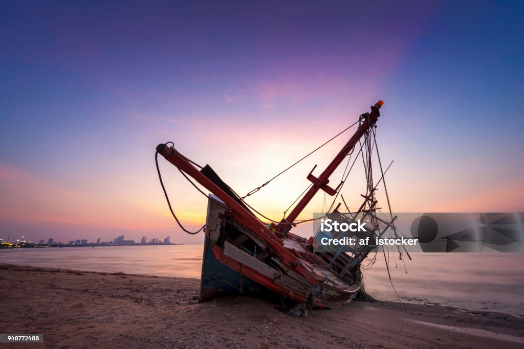 Abandoned shipwreck of wood fishing boat Abandoned shipwreck of wood fishing boat on beach at twilight time Ship Stock Photo