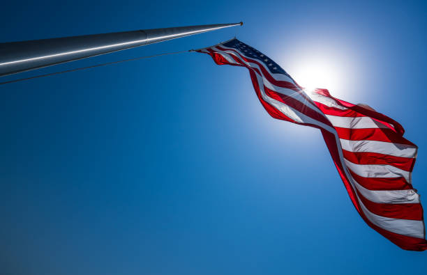 American Flag perfect flagpole and looking into sun American Flag perfect flagpole and looking into sun with perfect blue sky pole photos stock pictures, royalty-free photos & images