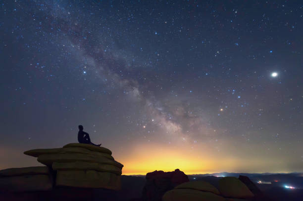 istock Man sitting on the rock under The Milky Way Galaxy 948778728