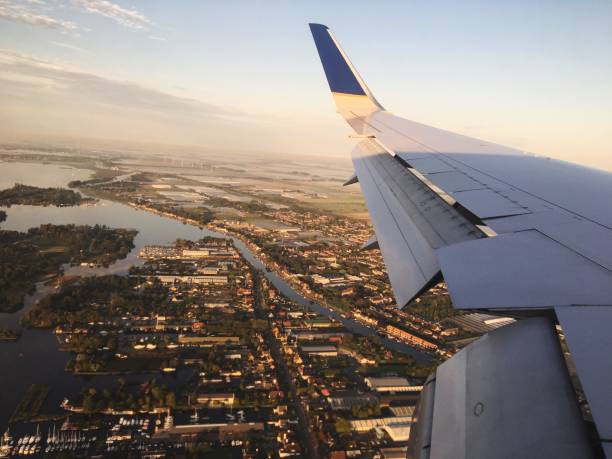 istock Cropped Image Of Airplane Wing Flying Over City During Sunset 948793330