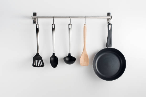 hanged kitchen utensils pans and utensils hanging on kitchen wall - utensílio de cozinha imagens e fotografias de stock