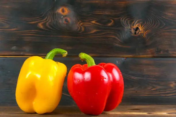 red and yellow bell peppers on wooden background