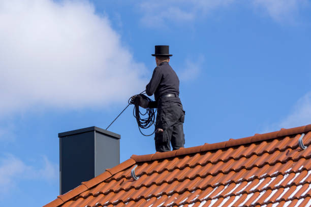 FISCHBACH, GERMANY - March 21 2018: Chimney sweep cleaning a chimney standing on the house roof, lowering equipment down the flue