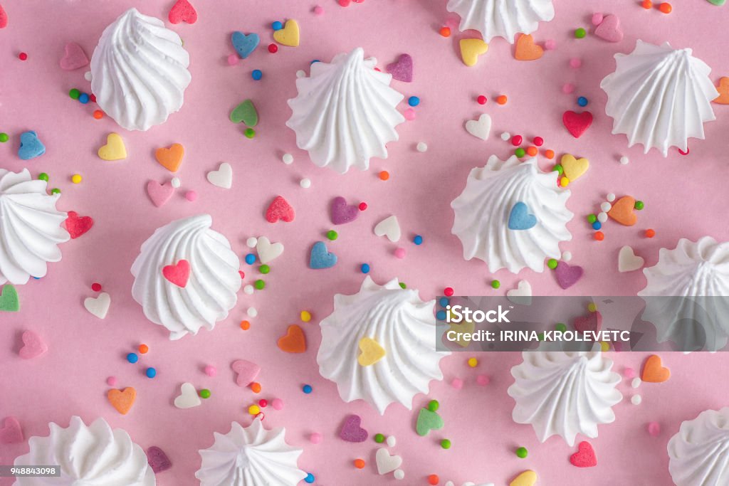 twisted meringues with confectionary decorations on pink background. Crispy white twisted meringues and with confectionary decorations on pink background Meringue Stock Photo