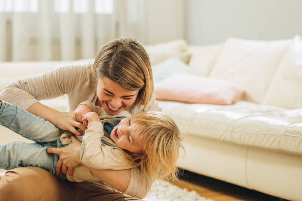 istock Young cheerful mother having fun while playing with her small boy at home. 948851850