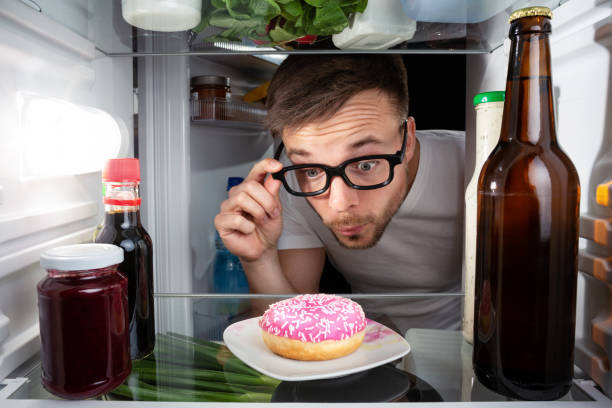 istock Man discovering a donut in the fridge 948856934