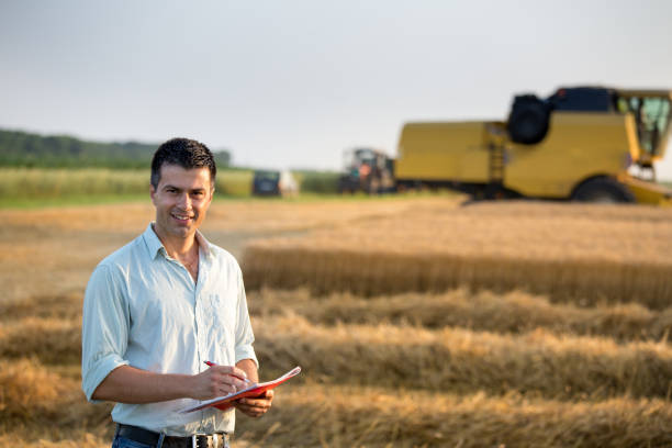 istock Farmer with notebook in front of combine harvester in field 948859880