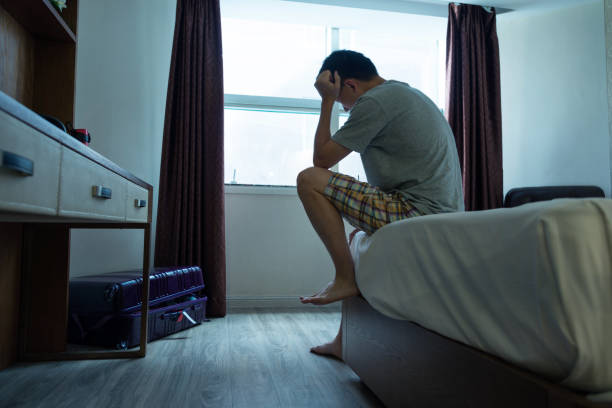 homem sentado na cama com a cabeça nas mãos - bag boredom bored man casual - fotografias e filmes do acervo