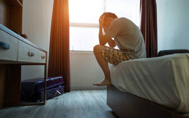 homem sentado na cama com a cabeça nas mãos - bag boredom bored man casual - fotografias e filmes do acervo