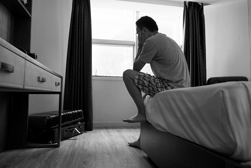 Man sitting on bed with hand on chin